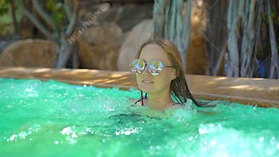 A young woman in a tropical resort with hot springs, waterfalls and swimming pools with hot mineral water. Slowmotion