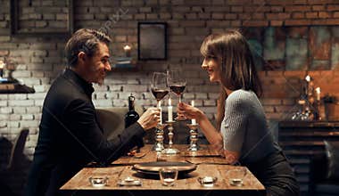 Happy couple drinking wine and having romantic dinner at home. Home date night, clinking wine glasses