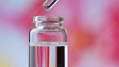 Blend of essential oils. Making some aroma liquids. Drops falling from pippet to little glass bottle.