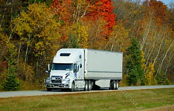 Ontario, Canada - October 27, 2019 - A large white truck on the Route 401 highway with stunning colors of fall foliage