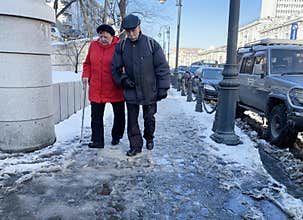 Vladivostok, Russia, March, 05,2020. Elderly couple of people walking down the street Aleutskaya in early spring. Vladivostok, Rus