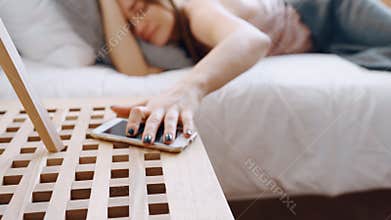 Tired girl sleep in cozy bed with orthopedic mattress chic bright apartment, phone with set alarm clock lies on wooden