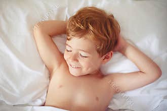 Cheerful boy sleep in bed.