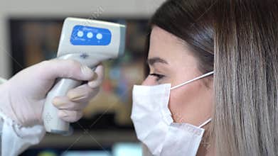 Taking a girl`s temperature with thermometer to find coronavirus, Covid-19. Close up shot.