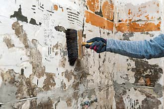 Hand with brush applying primer on the wall