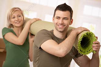 Happy couple carrying carpet together