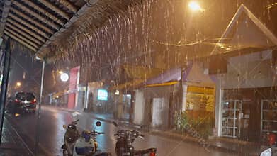 Rainy night, the night street of Bali during the rain, wet scooters stand on the street lit by lanterns