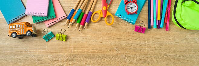Back to school banner with school supplies on wooden desk background. Top view, flat lay