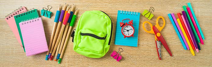 Back to school banner with school supplies on wooden desk background. Top view, flat lay