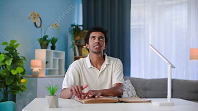 young black man with poor eyesight reading a braille book running his fingers over a page with letters sitting at a