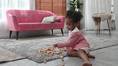 4K Little african girl sit on floor at home play construct tower with wooden bricks