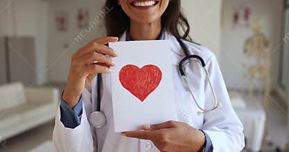 Female cardiologist showing to camera postcard with drawn red heart