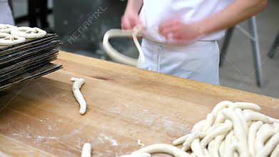 Baker forming pretzel from dough in bakery