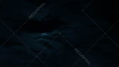 Bright full moon behind fast moving dark clouds on night sky