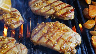 cooking pork loin chops on grill, barbecue, hot cast iron grate. close up. meat lubricate Dijon mustard