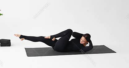A yoga instructor performs an exercise asymmetrical navasana in dynamics or a bicycle with twisting