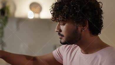 Concept of unhealthy food delivery. Hindu guy enjoying his hamburger. Young man with kinky hair biting tasty burger in