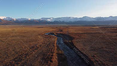 Amazing view of dry grass land with flowing water brook in daylight