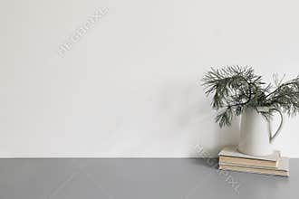 Elegant Christmas interior, home office. Ceramic vase, jug with green pine tree branches on old books. Winter home decor