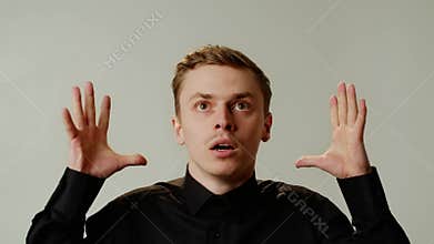 Young funny caucasian guy grimacing mind explosion on isolated on gray background. An emotional man in black shirt