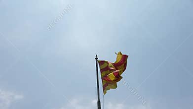 A Catalan flag flies in the wind against a blue sky