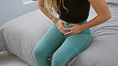 Beautiful young hispanic woman suffering with menstrual pain, touching aching stomach, sitting on bed in morning. portrait of a