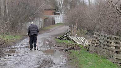 An old man walks down a dirt road among the ruins. Ukraine war. Chernihiv.