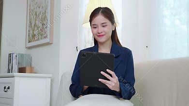 Happiness young asian businesswoman sitting on sofa using tablet computer for planning success business.