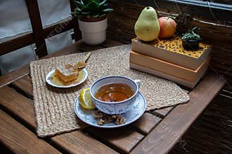 Morning setup on wooden table at balcony for morning relaxation with books, cup of tea, teapot, organic honey, green tea leaves