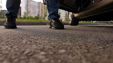 An irresponsible man gets out of the car and throws a plastic bag with various garbage on the asphalt.
