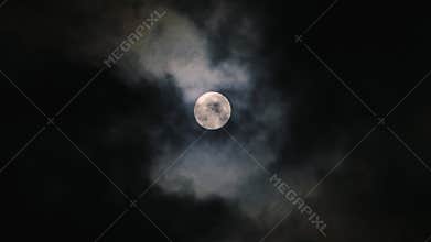 Clouds passing Moon in dark night sky