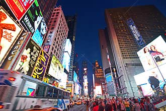 Lit up New York Time Square, USA evening after work rush hour with congested traffic road bus, taxi passing by & busy human crowd