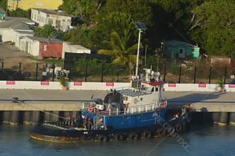Docked Tugboat in Antigua Harbor with Colorful Shoreline Background