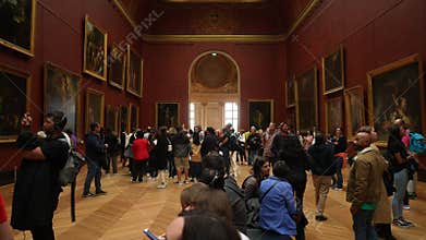 Paris, France - 3 May 2023. Diverse visitors watching famous pictures walking on hall and sitting on bench sightseeing