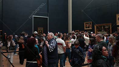 Paris, France - 3 May 2023. Tourists looking at museum painting and listening audio guide walking sightseeing Louvre