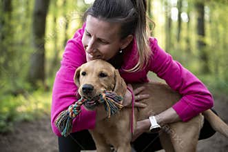 Young dog owner cuddling with her playful puppy