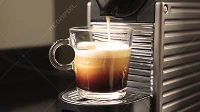 A cup of frothy espresso coffee freshly brewed from the machine.