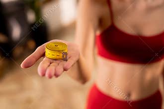 Selective focus of sporty woman holding measuring tape. Losing weight concept, calories control