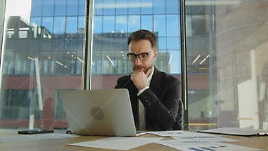 Mature concentrated businessman trader working looking at laptop computer screen thinking analyzing online trading