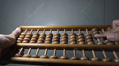 abacus. sempoa. Made of wood. An Asian man's hand is focused on counting.