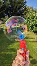 A big bubble made by a red bubble gun in the garden