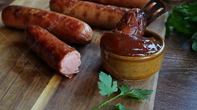 Grilled sausages Bockwurst dipped in red sauce. Close up. Slow motion.