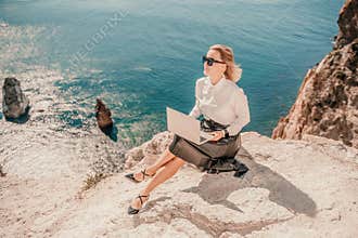 Business woman on nature in white shirt and black skirt. She works with an iPad in the open air with a beautiful view of