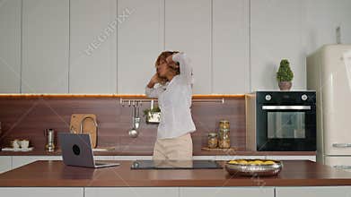 woman with blond curly hair dancing in kitchen