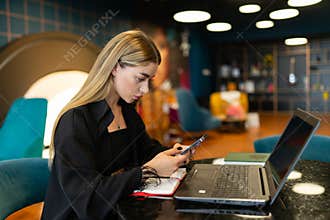 Focused woman uses smartphone for work purposes in office