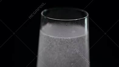 A glass of mineral water on a dark background, close-up.