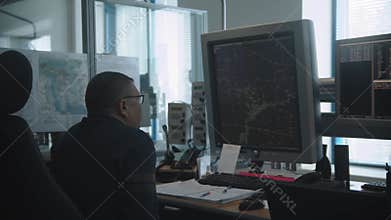 Navigation room in the airport - an old man working with a monitor with fly paths placed on the map
