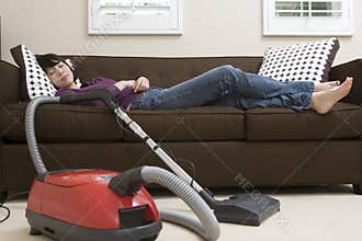 Woman Relaxing On Couch With Vacuum Cleaner