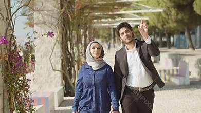Medium shot of Arabic couple, walking along alley
