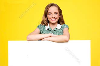 Girl posing behind an advertising board